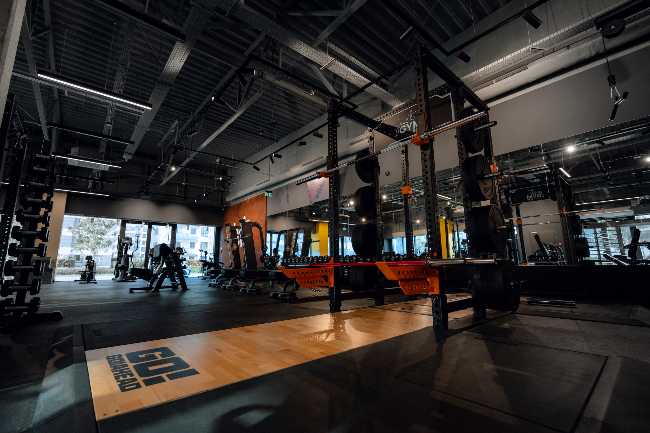 Główna sala treningowa Just Gym Box Warszaw – rig, platforma ciężarowa i sprzęt siłowy w industrialnym wnętrzu.